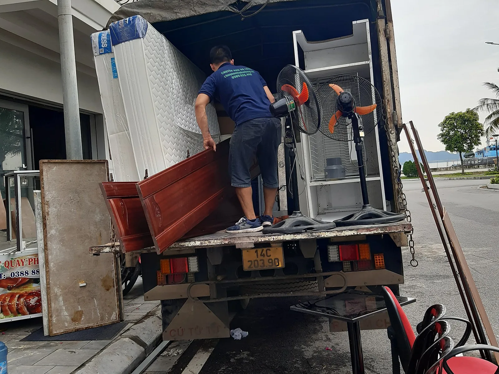 Thợ bốc đồ lên xe tải trước dãy shophouse ven biển